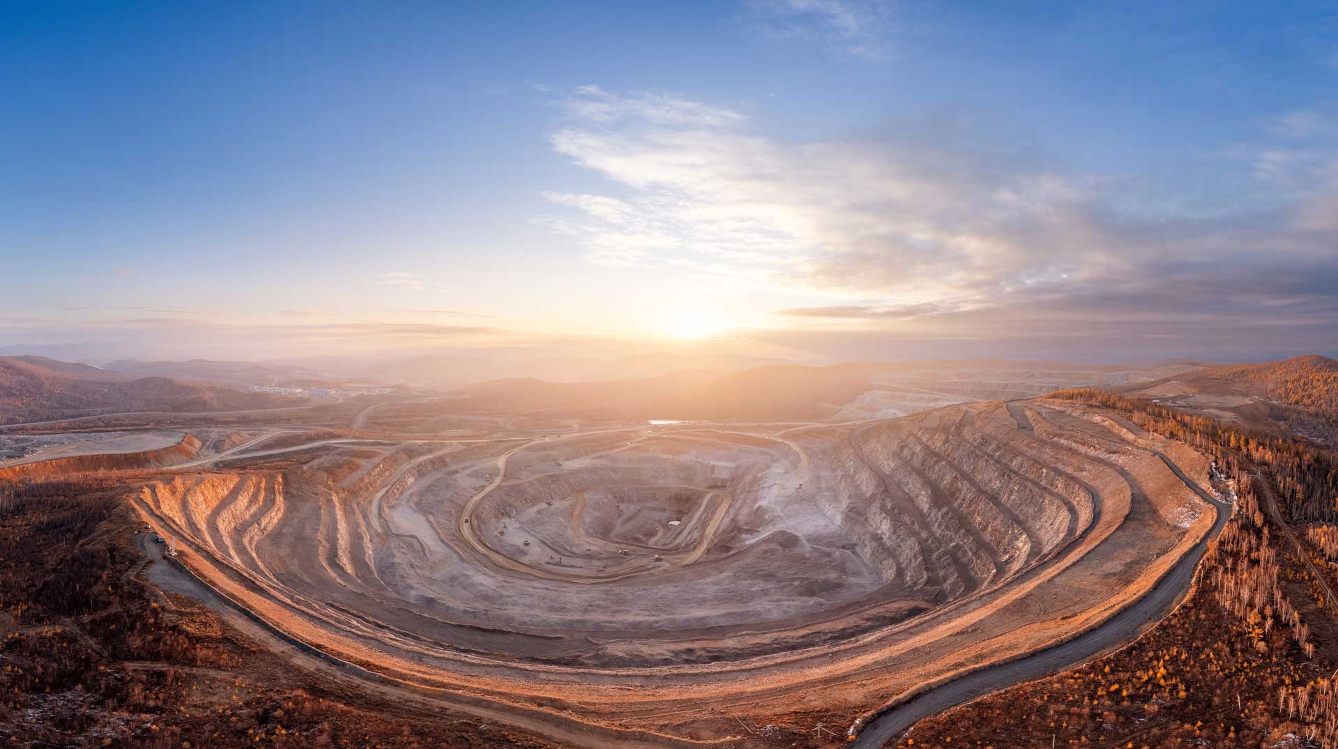 The sun rising above a massive mine site