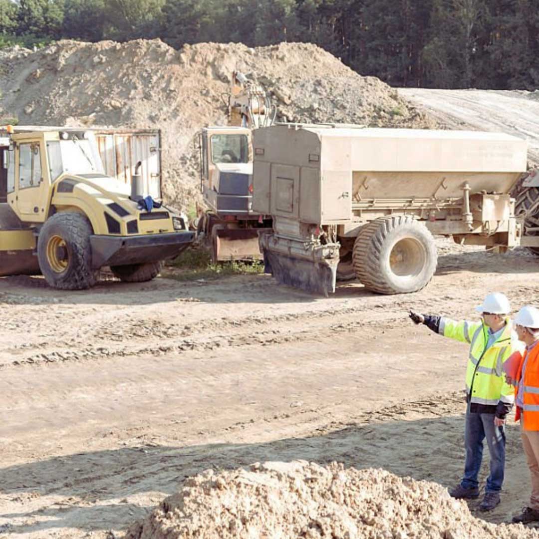 Workers on a mine site wearing hi viz vests pointing towards some trucks